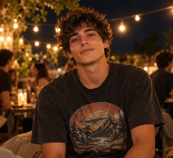 Young man in a vintage graphic T-shirt under warm string lights at night